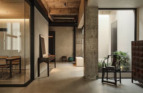 Rustic industrial loft interior with exposed concrete walls, wooden beams, and antique furnishings.