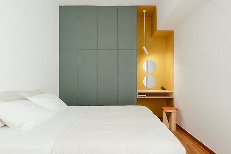 Modern bedroom design with built-in closet, wooden floors, and vibrant yellow accent.