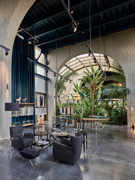 Expansive industrial-style lobby featuring lush greenery, curved glass windows, and modern furnishings.
