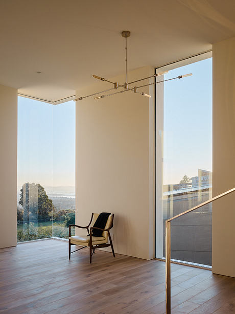 Minimalist interior with contemporary lighting fixture, wooden floors, and expansive window.