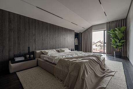 Sleek, modern bedroom with dark wooden paneling, recessed lighting, and a large window.
