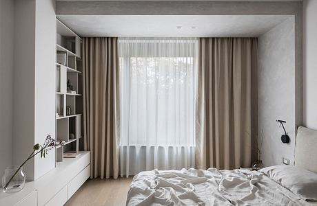 A minimalist, modern bedroom with clean lines, neutral tones, and a stylish shelving unit.