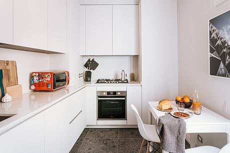 Sleek, modern kitchen with white cabinets, stainless steel appliances, and a dining area.