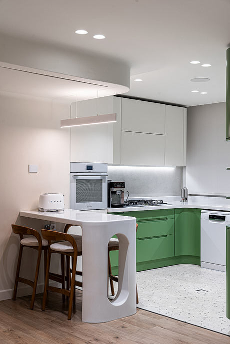 Sleek, modern kitchen with minimalist green cabinets, pendant lighting, and wooden barstools.