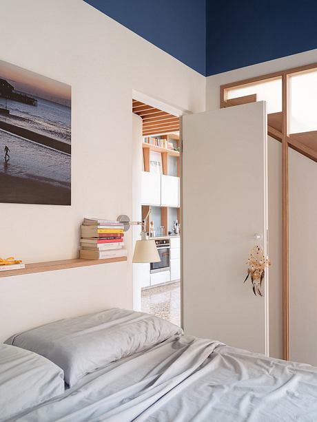 A cozy bedroom with wooden shelving, modern lighting, and a dreamcatcher on the wall.