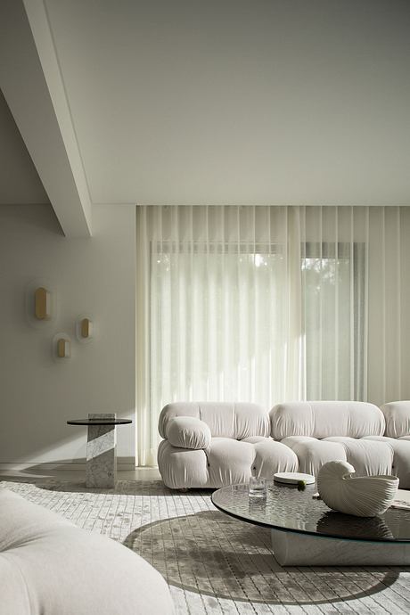 A minimalist living room with a plush white sofa, glass coffee table, and textured walls.