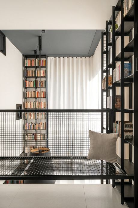 Minimalist living space with sleek black metal shelves, curtains, and a cozy reading nook.