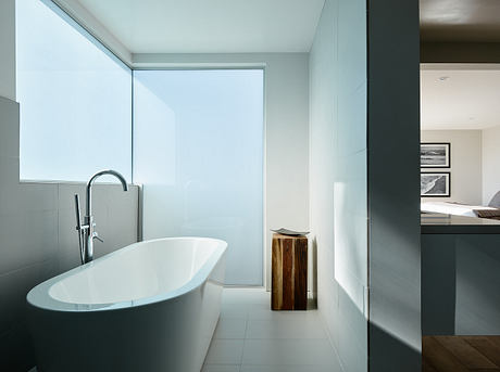 Minimalist, modern bathroom with freestanding bathtub, wooden vanity, and sleek fixtures.