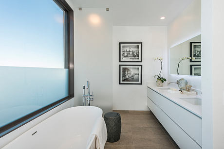 Elegant modern bathroom with white tub, black and white framed art, and sleek vanity.