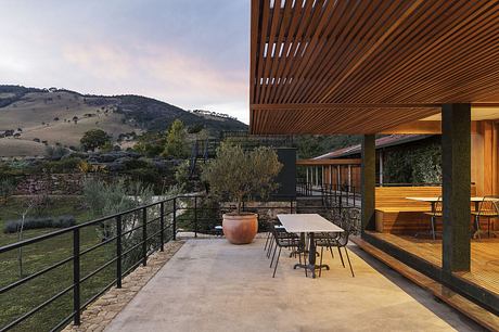 Expansive wooden deck with modern furnishings overlooking rolling hills and trees.