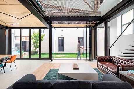 A modern open-plan office space with glass walls, industrial ceiling, and mix of furniture.