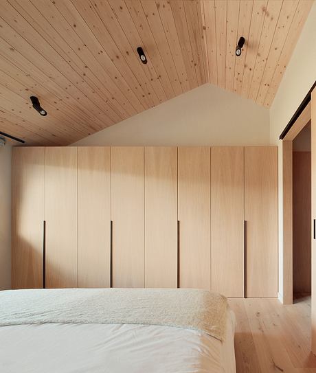 Cozy wooden bedroom with built-in closet cabinets and sloped ceiling.
