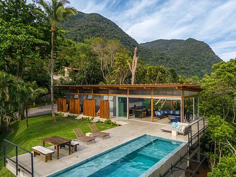 A modern tropical villa with an open-plan living space, pool, and stunning mountain view.