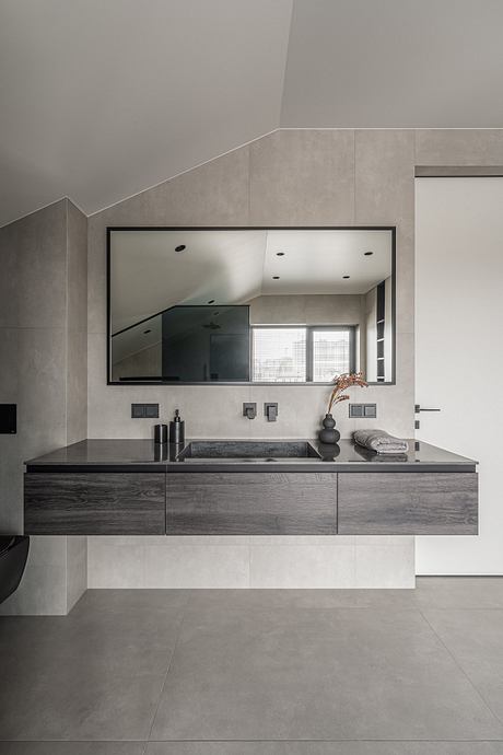 A modern bathroom with a sleek black vanity, minimalist mirror, and modern fixtures.