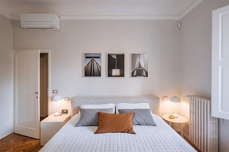 Minimalist bedroom with modern art prints, neutral colors, and functional lighting.