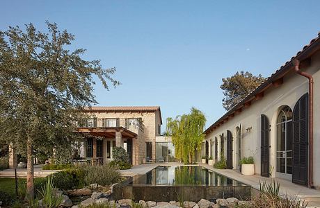 Elegant Spanish-style villa with a serene reflecting pool, lush landscaping, and arched windows.