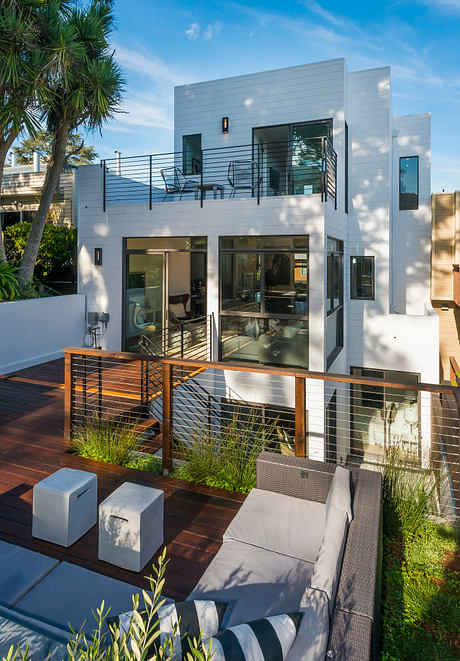 Contemporary two-story home with sleek exterior, expansive deck, and lush landscaping.