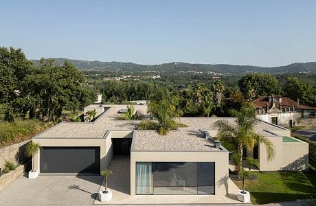 Modern home with clean lines, flat roof, and large glass panels overlooking lush, hilly landscape.