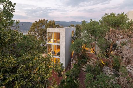 A modern, multi-level concrete structure nestled among lush greenery and rocky terrain.