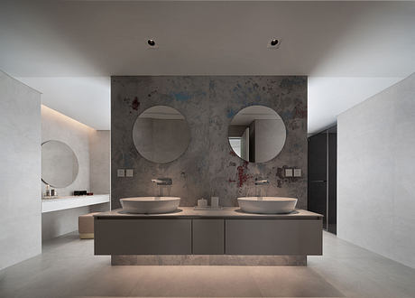 A modern, minimalist bathroom with a marble-clad wall, double vanity, and round mirrors.
