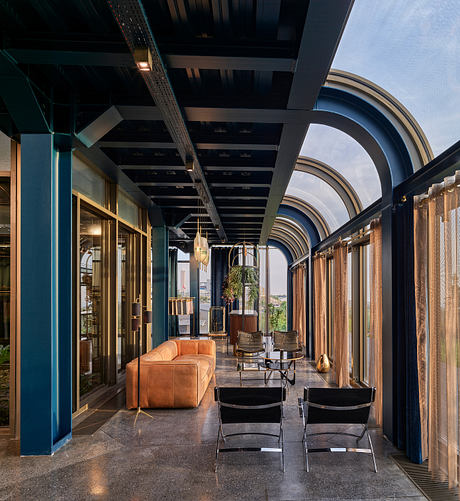 A modern, industrial-style interior space with arched windows, wooden beams, and leather seating.