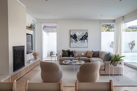 Bright, modern living room with minimalist furniture, artwork, and views to the outdoors.