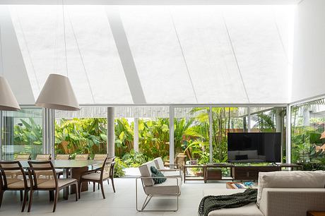 Expansive glass walls framed by tropical foliage create a seamless indoor-outdoor experience.