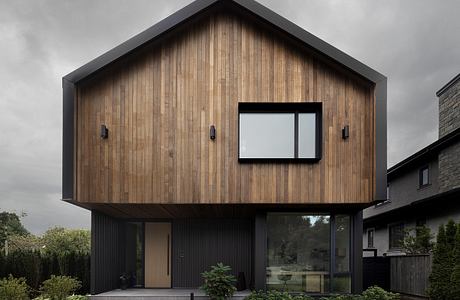 Modern wooden house with black trim, large windows, and a sleek, minimalist design.