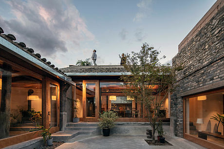 Stunning courtyard design with stone walls, glass doors, lush greenery, and ambient lighting.