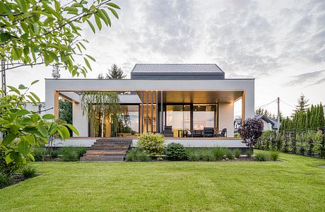 Modern home with large glass walls, wooden accents, and landscaped yard.