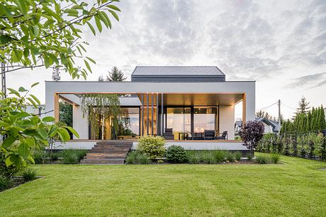 Modern home with large glass walls, wooden accents, and landscaped yard.