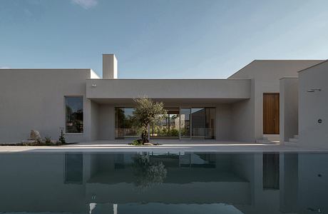 Sleek, modern architecture featuring a minimalist design with glass walls, a pool, and landscaping.