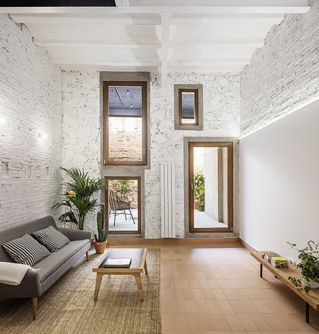 Rustic-style living room with exposed brick walls, large windows, and wooden furnishings.