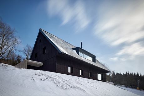 A modern chalet-style cabin with a sleek, angular roofline and large windows.