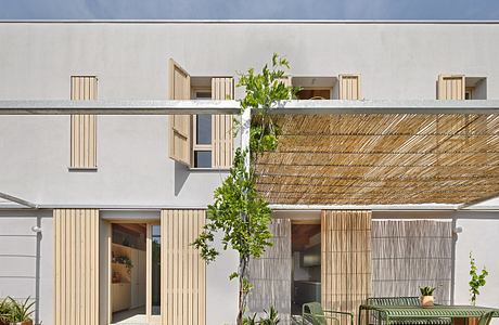 Contemporary exterior with wooden screens, potted plants, and minimal furniture.