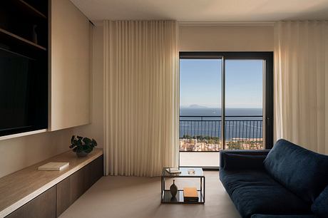 Serene living space with floor-to-ceiling windows offering panoramic sea views and minimalist furnishings.