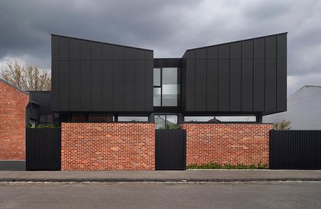 Modern black and red brick building with geometric architectural details.