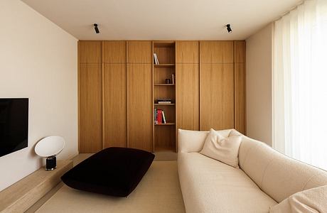 A cozy living space with a minimalist wooden wall unit, beige sofa, and low coffee table.