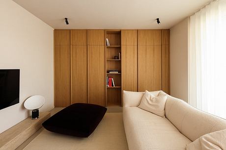 A cozy living space with a minimalist wooden wall unit, beige sofa, and low coffee table.