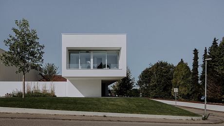 A modern, minimalist concrete and glass building with a cantilevered design.