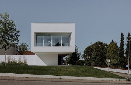 A modern, minimalist concrete and glass building with a cantilevered design.