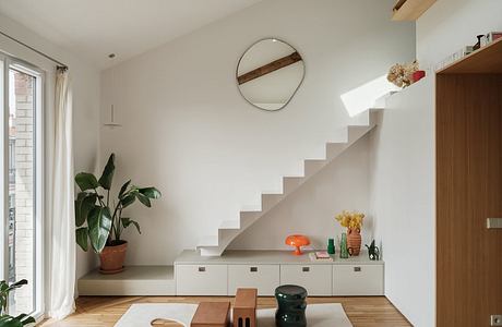 Bright, minimalist interior with curved staircase, built-in storage, and natural materials.