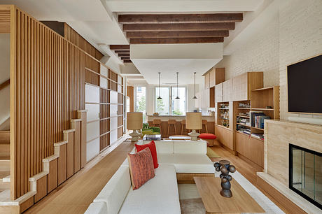 Wooden beams, built-in shelves, and a cozy seating area in this modern, open-concept space.