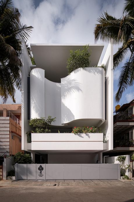 Striking modern tropical home with dramatic curved walls, greenery, and clean lines.