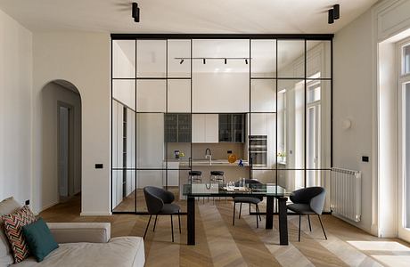 Contemporary open-concept living space with sleek glass partition, mod furnishings.