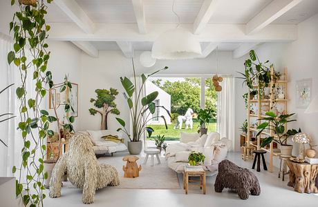 Airy, plant-filled living space with high ceilings, plush seating, and natural decor.