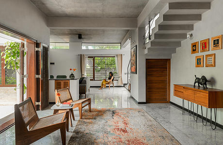 Minimalist living space with concrete walls, wooden furniture, and vibrant artwork.