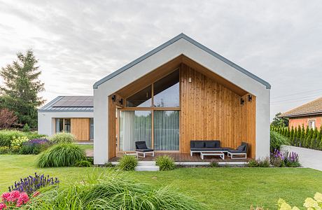 A modern house with a wooden exterior, glass walls, and a covered patio area.