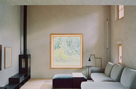 A minimalist living room with a framed nature scene, sleek furniture, and warm lighting.