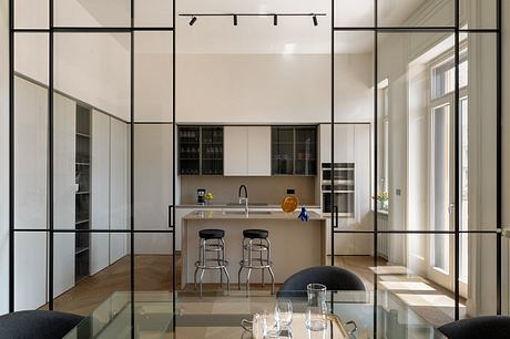 Modern open-concept kitchen with sleek black-framed windows, minimalist cabinetry, and bar stools.